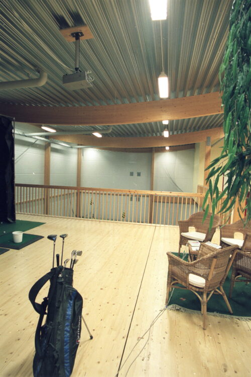 Golfbag på en terrass med lounge area i en golfhall.