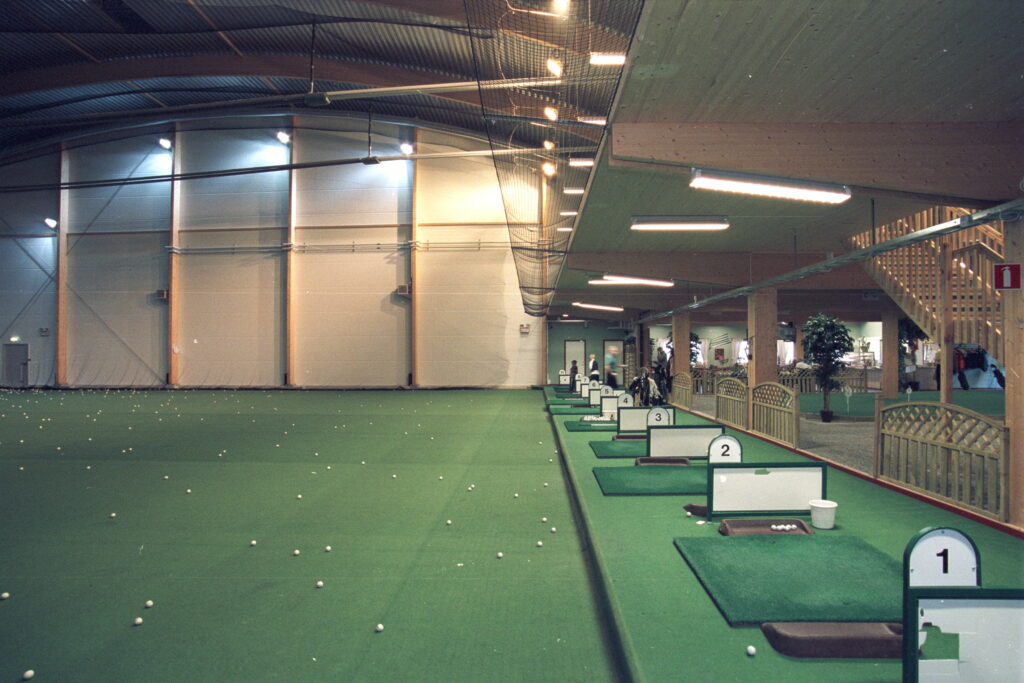 Insidan av en golfhall av limträ med driving range.